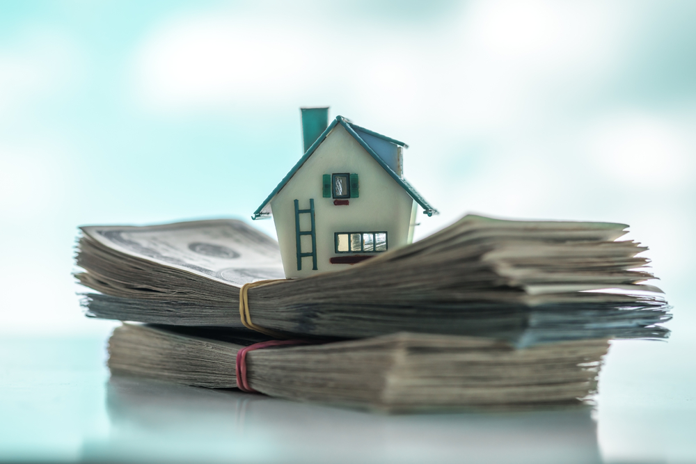 Tiny home sitting on top of stack of money
